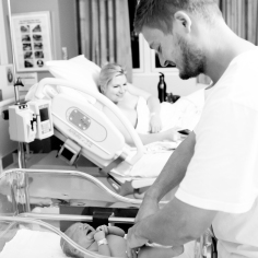 dad dressing fresh newborn baby in hospital
